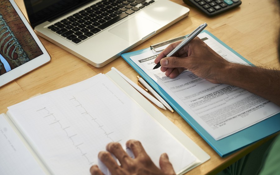 Hands completing a form at a desk
