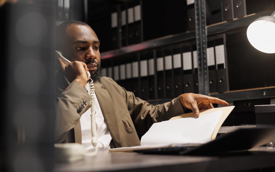 Man reviewing a file during a telephone conversation